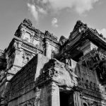 Black and white photo of intricate ancient temple architecture with cloudy sky background.