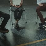 The Illusion of Consensus: Why Participation Limits Strategy A group of three adults sitting in chairs during a discussion or support session indoors.