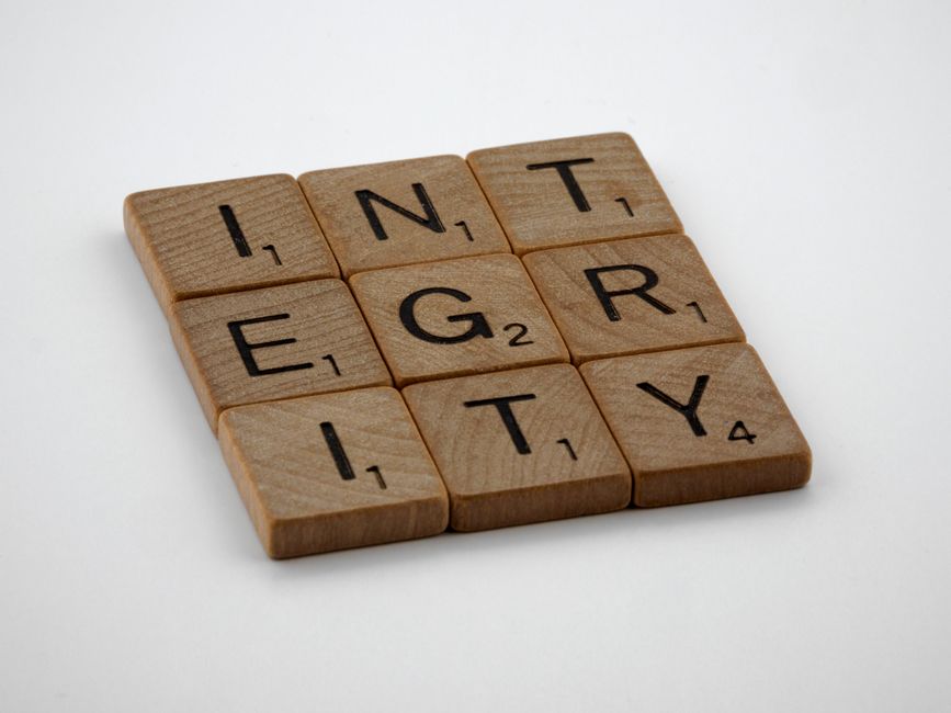 Wooden scrabble tiles spelling 'INTEGRITY' on a white background, emphasizing honesty and ethics.