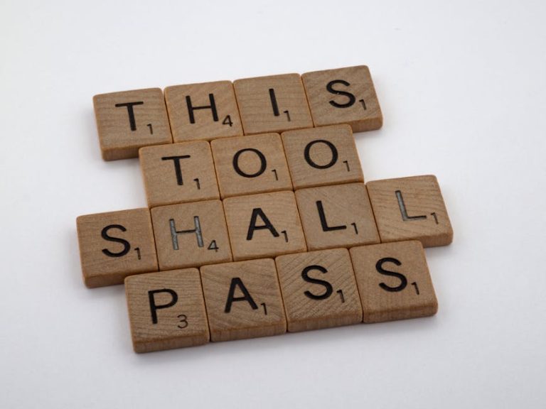 Wooden tiles form the motivational message 'This too shall pass,' highlighting resilience.