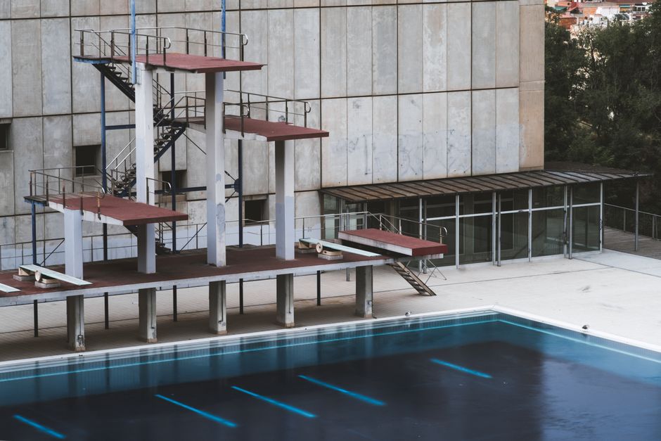 Empty swimming pool with diving platforms in Barcelona, showcasing urban decay.