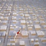 The Invisible Architecture of Performance: Strategic Management A woman artistically poses on a concrete block grid outdoors, showcasing balance and creativity.