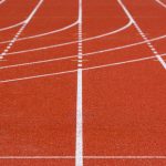 The Invisible Infrastructure of Competitive Advantage Explained A detailed view of an empty red running track with crisp white lanes, perfect for athletics.