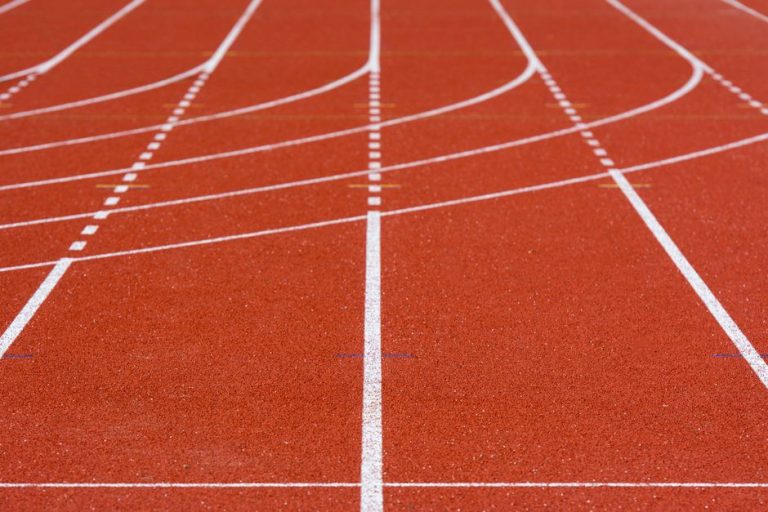 A detailed view of an empty red running track with crisp white lanes, perfect for athletics.