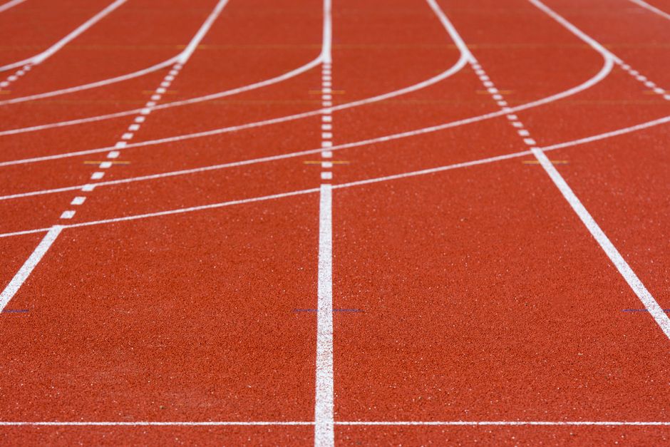 A detailed view of an empty red running track with crisp white lanes, perfect for athletics.