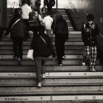 The Just-in-Time Trap: Why Your Efficiency is Your Greatest Liability Monochrome image of people using subway stairs, emphasizing urban daily routine.