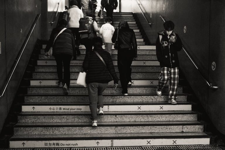 Monochrome image of people using subway stairs, emphasizing urban daily routine.