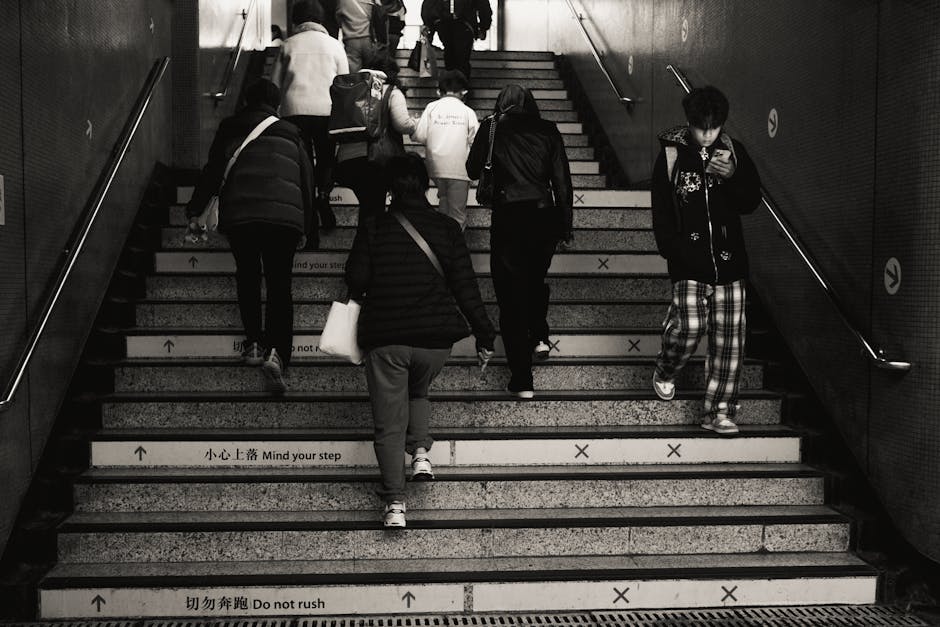 Monochrome image of people using subway stairs, emphasizing urban daily routine.