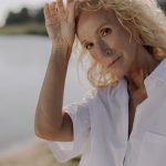 The Longevity Alpha: Why Aging Populations are the Ultimate Innovation Catalyst Portrait of a senior woman with blonde hair posing outdoors in sunlight.