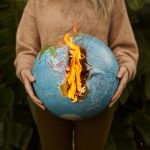 The Moral Hazard of Planetary Control: Governance and Strategy A symbolic portrayal of climate change with a burning globe held in hands, set against a nature background.