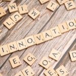 The Myth of Disruptive Breakthroughs: Strategy Over Inspiration Creative display of 'Innovation' spelled with wooden letter tiles on a wooden surface.