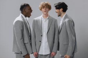 Three men in gray suits demonstrating conflict in a professional setting.
