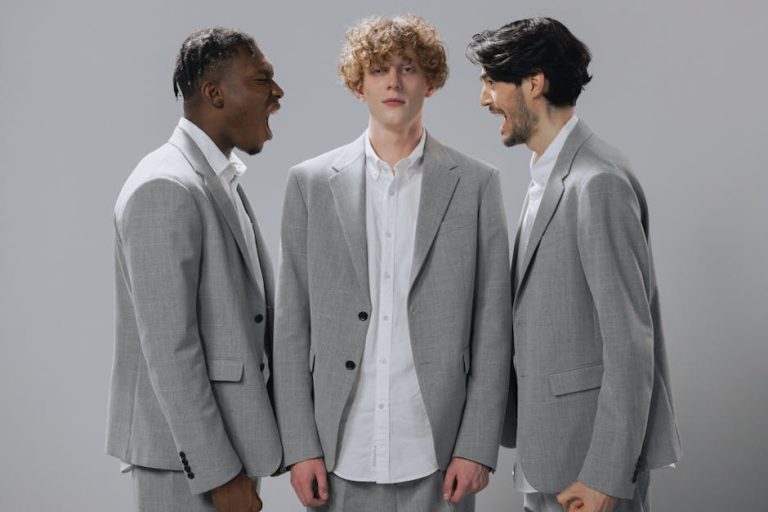Three men in gray suits demonstrating conflict in a professional setting.