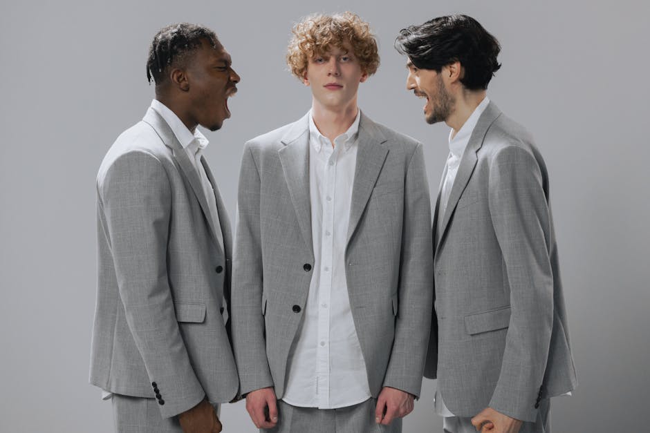 Three men in gray suits demonstrating conflict in a professional setting.