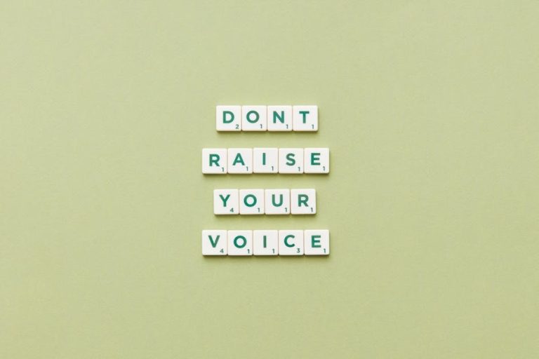 Scrabble tiles spelling 'Don't Raise Your Voice' on a green background.