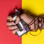 The Obsolescence Trap: Why Your Best Employees Are Resisting Your Best Tech Hand holding tangled cassette tape on vibrant red and yellow background, representing nostalgia.