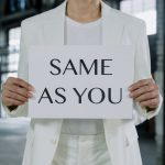 The Outsourcing Fallacy: Why You Should Insource Your Operational DNA A person in a white suit holds a sign reading 'Same as You', promoting equality.