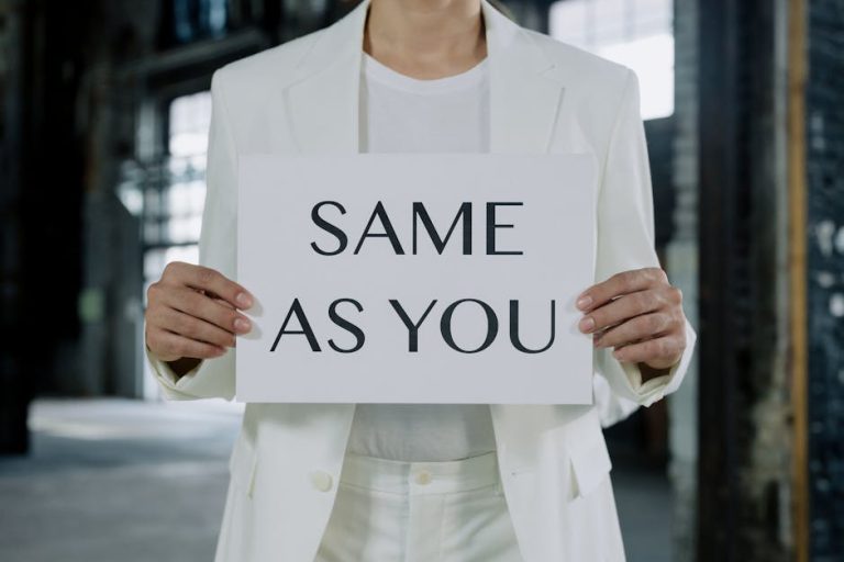 A person in a white suit holds a sign reading 'Same as You', promoting equality.
