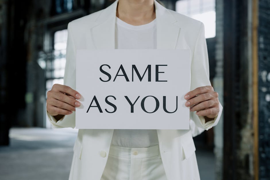 A person in a white suit holds a sign reading 'Same as You', promoting equality.