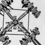 Exciting black and white shot of a pendulum ride in action at an amusement park.