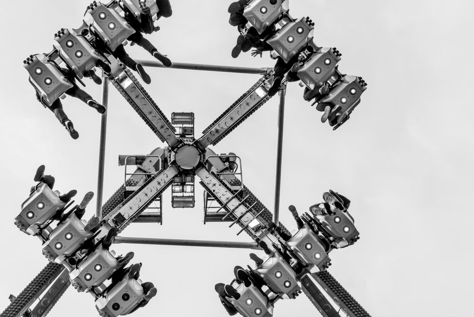Exciting black and white shot of a pendulum ride in action at an amusement park.