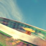 Dynamic long exposure capture of a colorful carnival ride against a bright blue sky.