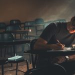 The Physics of Persistence: Ion Propulsion for Business Growth Student focused on writing, studying in a dimly lit empty classroom.