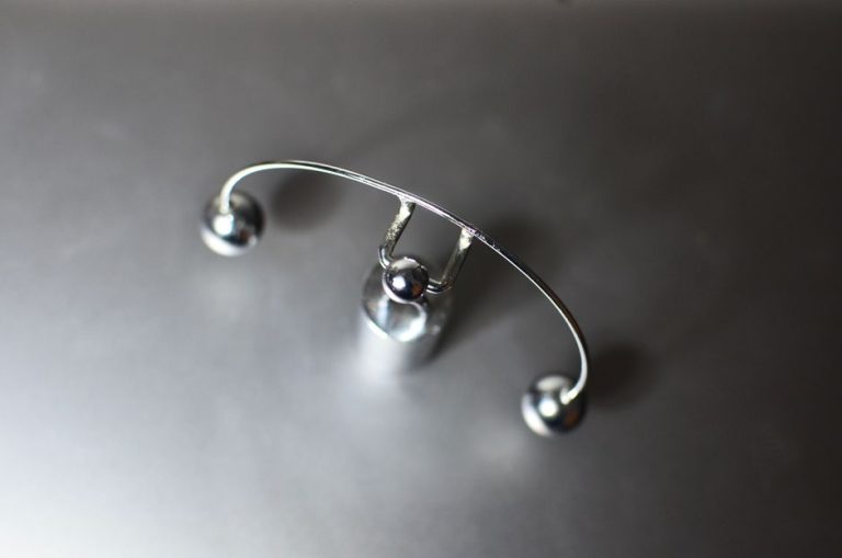 Top view of metal kinetic weightlifter cradle toy with balance balls placed on gray background in light room on blurred background