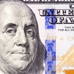 Detailed close-up of Benjamin Franklin's portrait on a 100 dollar bill showing July 4, 1776.