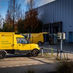 Deutsche Post electric delivery vans parked outdoors emphasizing sustainable logistics.