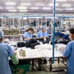 The Post-Labor Economy: Why Human Effort No Longer Equals Value Blue-collar workers organize textiles in a busy factory setting.