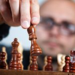 The Precision Paradox: Strategic Ablation for Business Growth Close-up of a chess player making a strategic move with a focus on the chess piece and the player's intent.