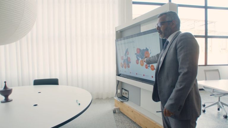 Professional in suit presenting data on screen in a modern office environment.