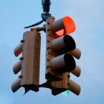Close-up of a red traffic light signaling stop against a clear blue sky.
