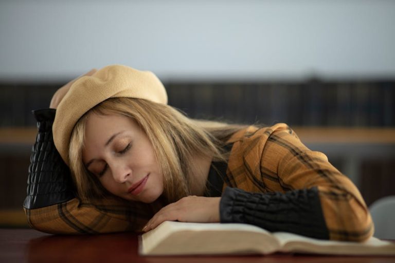 A young woman in a library naps on an open book with eyes closed, wearing a beret hat.