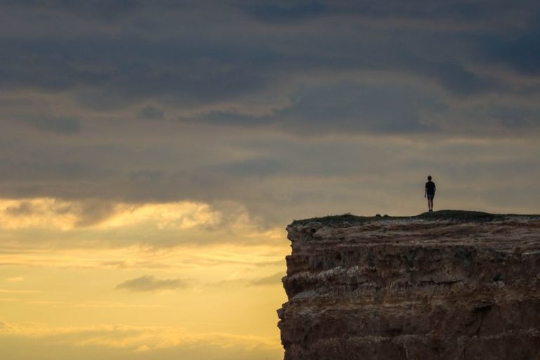 A person stands on a cliff edge at sunset in Mar del Plata, offering a dramatic view.