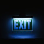Photo of a glowing green exit sign in a dark environment, symbolizing safety and direction.