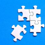 The Strategic Paradox of Disconnection: Why Great Leaders Must Know When to Withdraw White jigsaw puzzle pieces against a solid blue background, showcasing a flat lay arrangement.