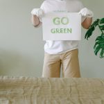 A person holding a 'Go Green' sign promoting environmental awareness indoors.