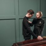 A grieving man and woman comfort each other at a funeral, expressing sorrow and loss.