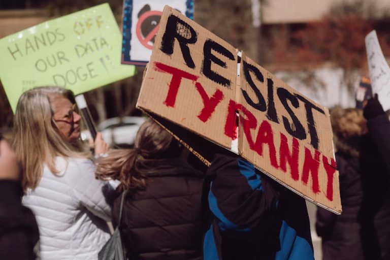 Protest scene with demonstrators holding signs expressing opposition to tyranny.