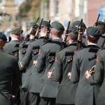 The Uniform of the Outsider: Why Strategic Minimalism is Your Greatest Competitive Edge A group of soldiers in uniforms holding firearms, marching through a street in an outdoor formation.