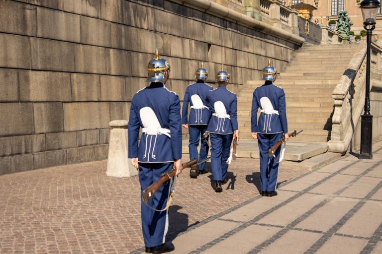 Swedish Royal Guards marching at Stockholm Palace on a sunny day.