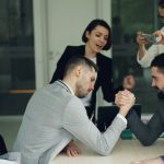 The Untranslatable Competitive Advantage: Why Monolingualism is a Strategy Blind Spot Colleagues cheer during a fun office arm wrestling challenge, fostering team spirit.