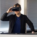 A young man immersed in a virtual reality experience indoors, using a VR headset.