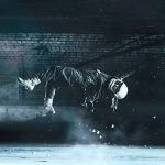 A cosmonaut floats effortlessly in an artistic fashion amidst a dimly lit indoor space.