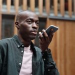 Voice-Activated Command: The New Standard for Executive Speed Stylish adult man using his smartphone for voice commands in an outdoor urban setting.