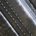 Water Management Strategy: A Key Operational Constraint for Biz Aerial view of a structured water flow over a weir with rhythmic patterns and concrete blocks.