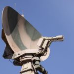 Weather Modification: Strategic Monitoring & Decision Science Close-up of a military radar system with a clear blue sky as background, showcasing advanced communication technology.