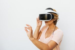 Woman using a VR headset immersed in a virtual reality world, with a white background.